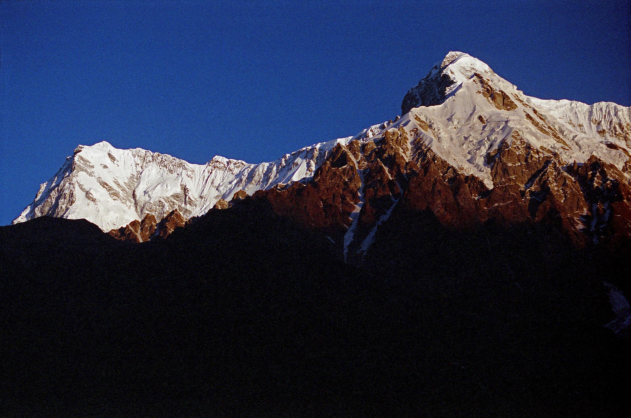 09 Nanga Parbat Rupal And East Faces, Rakhiot Peak From Tarashing At Sunrise The yellow light of sunrise quickly changes to white on the Nanga Parbat Rupal and East Faces from Tarashing. Rakhiot Peak is on the right. Gunther Messners diary May 15, 1970: The day dawns bright and cloudless. For the first time I see Nanga and Chongra Peak from the south: the impression is overwhelming. Huge hanging glaciers, terrifying precipices, furrowed by avalanches. Right over to the left is the summit of Nanga! (The Naked Mountain by Reinhold Messner)